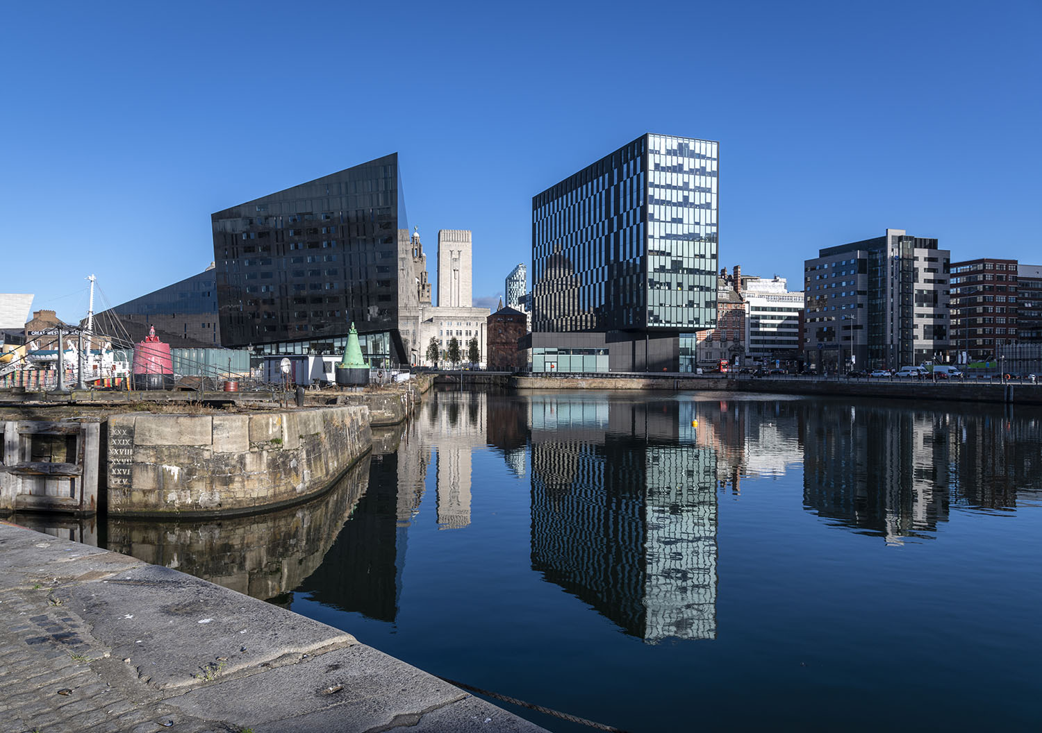 Serene looking scene of still water across the iconic Albert Dock looking towards the dramatic modern architecture of the renovated Mann Island area.